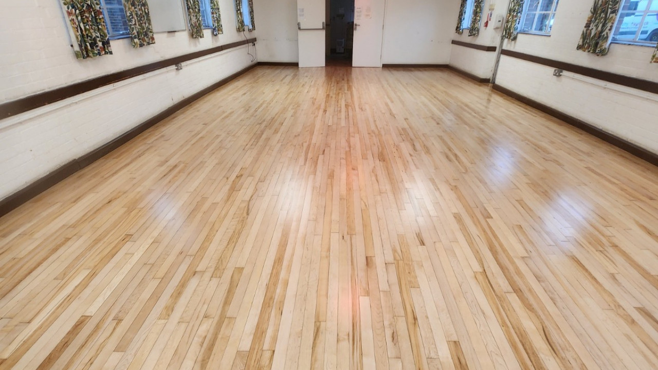 A fully restored and polished Junckers SylvaKet Beech solid hardwood floor after professional school hall maintenance.
