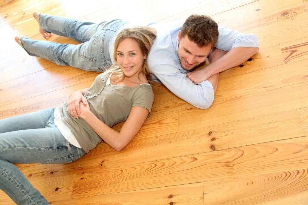  A happy couple relaxing on their newly sanded and refinished pine wood floor in Twickenham, UK. The floor, beautifully restored by Mr. Sander®, showcases the natural grain and warm tones of the pine wood, creating a cozy and inviting living space.
