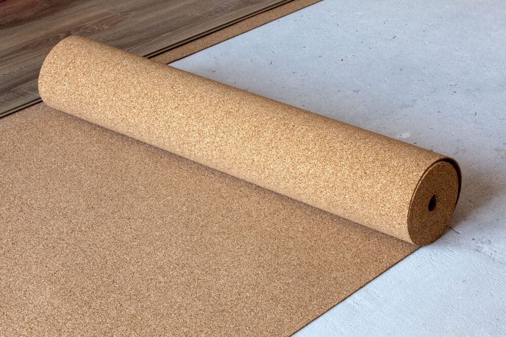 Rolled cork underlayment on a concrete floor next to wooden flooring.