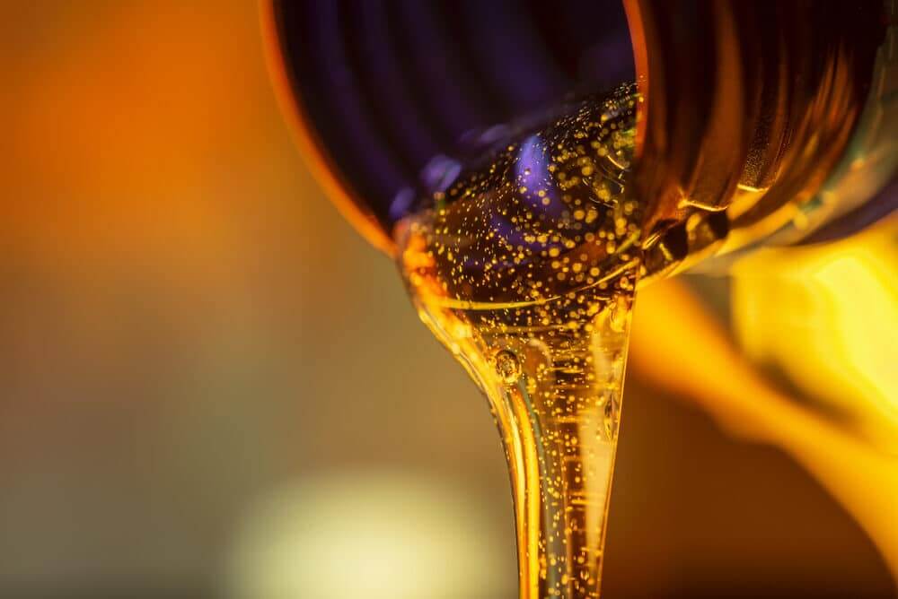 Close-up of honey pouring from a spoon with a vibrant, blurred background.