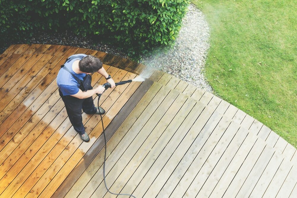 Overhead view of a person power washing a semicircular wooden deck.