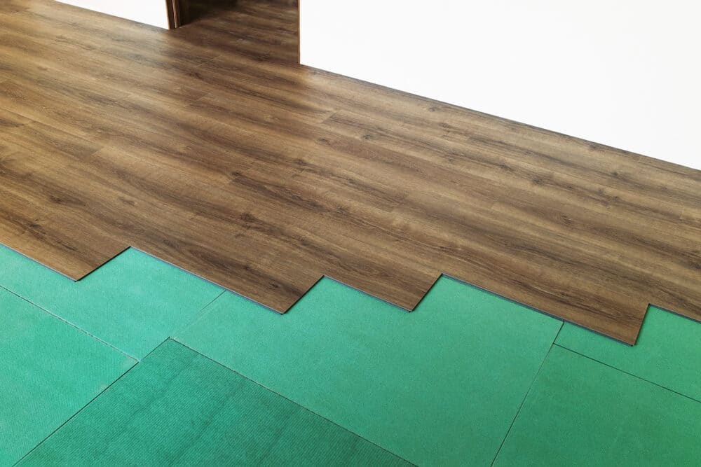 Wooden flooring transitioning to green carpet tiles.