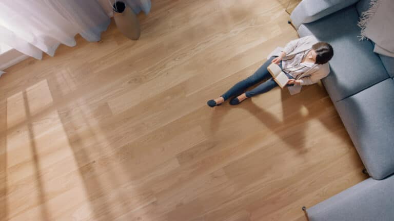Young,Woman,Is,Sitting,On,A,Floor,And,Reading,A