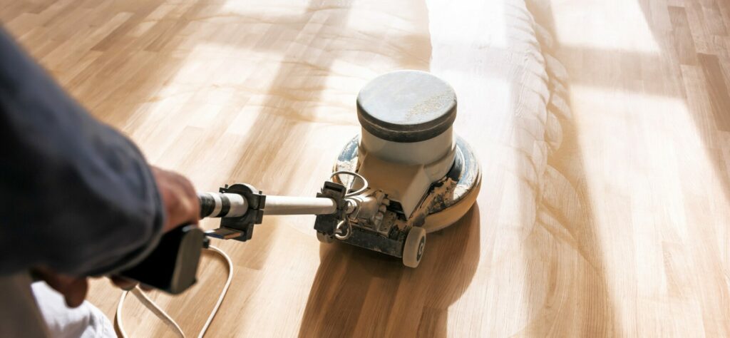 Mr. Sander® professional sanding oak floor with single disk sanding machinein a living room of a home in Barbican. UK. Intermediate sanding in progress, enhancing wood surface.