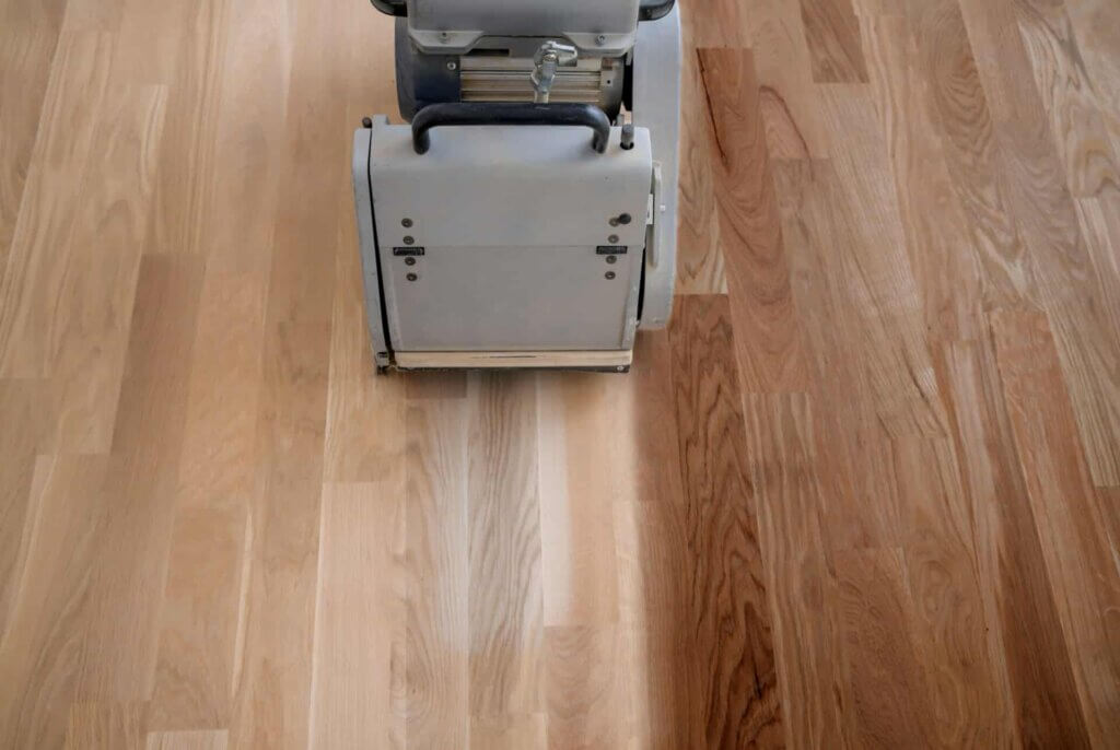 Man from Mr Sander® sanding an oak floor in a living room in Bloomsbury, UK, using a Bona Belt sander (AMO110000.3). Machine specs: 2.2 kW power, 230 V, 50 Hz, drum width 200 & 250 mm, sanding belt size 200 x 750 mm or 250 x 750 mm, motor power 1-phase Europe/Asia 2.2 kW, total weight 74 kg.