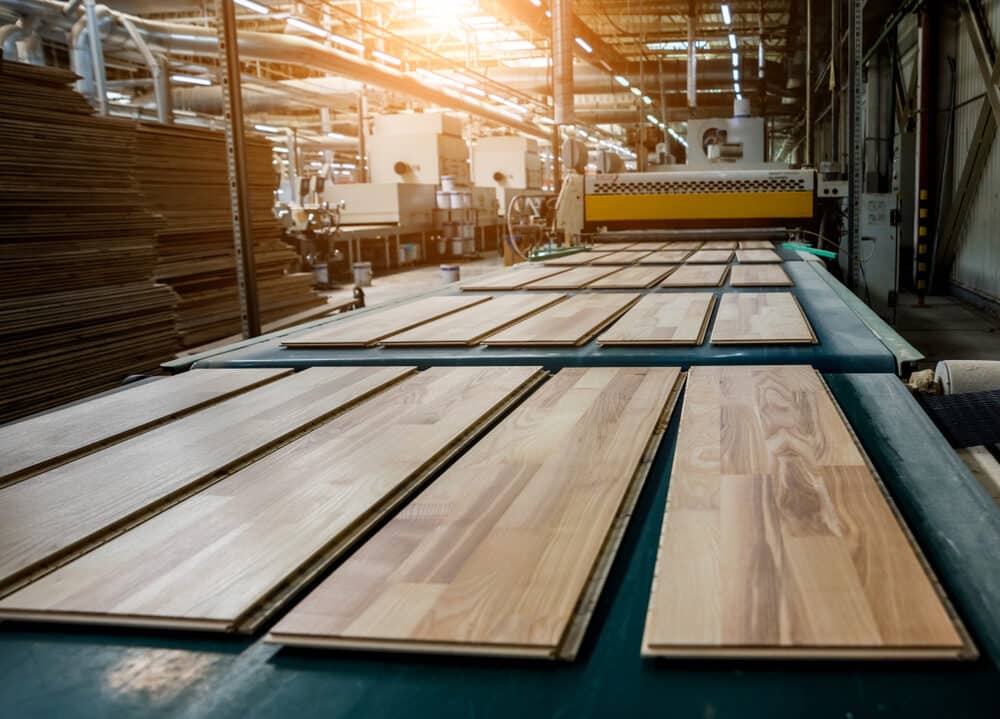 Wooden panels being manufactured on an industrial conveyor belt in a factory setting.