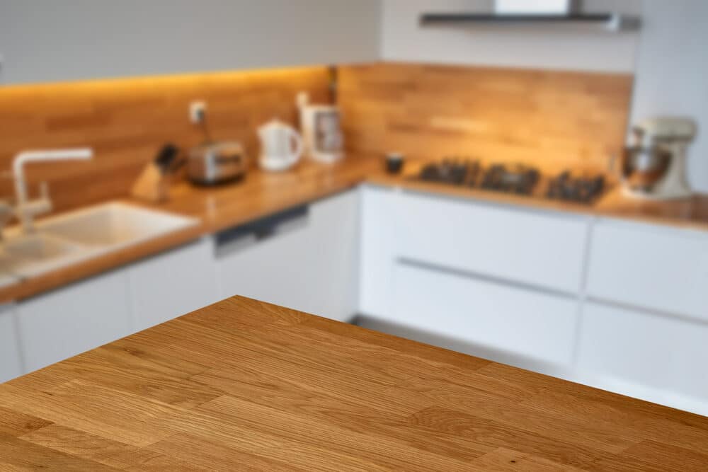 A modern kitchen counter in focus with a blurred background showcasing a kitchen interior.