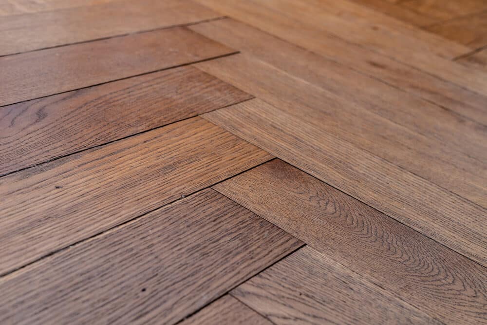 Close-up of a herringbone patterned wooden floor with a rich dark stain.
