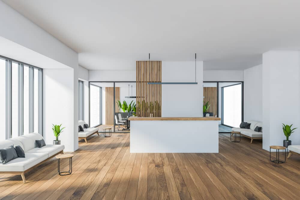 Modern open-plan living space with expansive wooden flooring, white walls, and minimalist furniture.