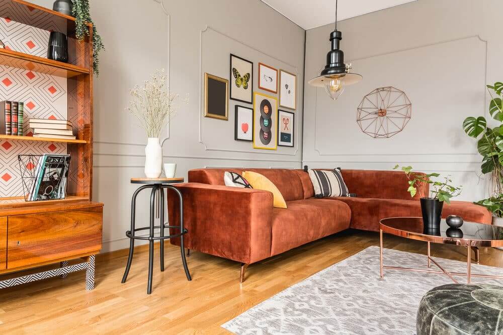 Stylish living room interior with a terracotta sofa, eclectic wall art, and modern furnishings