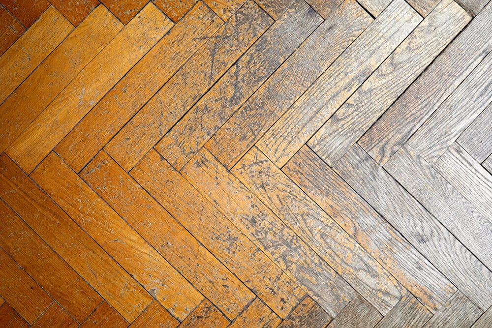 A close-up view of a wooden floor where two different types of wood meet, showing a contrast in color and texture.