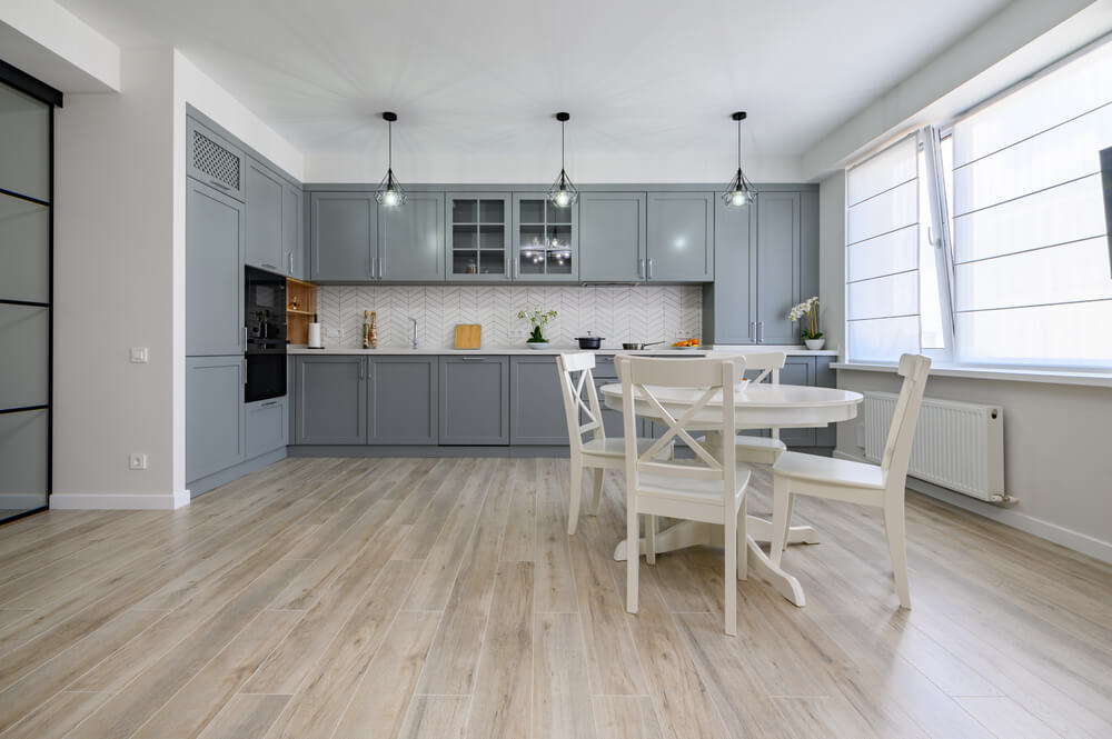 Bright and airy kitchen interior with gray cabinetry and a white dining set.