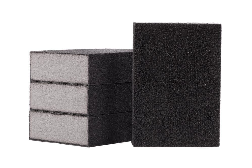 A stack of black and gray foam sanding blocks on a white background.