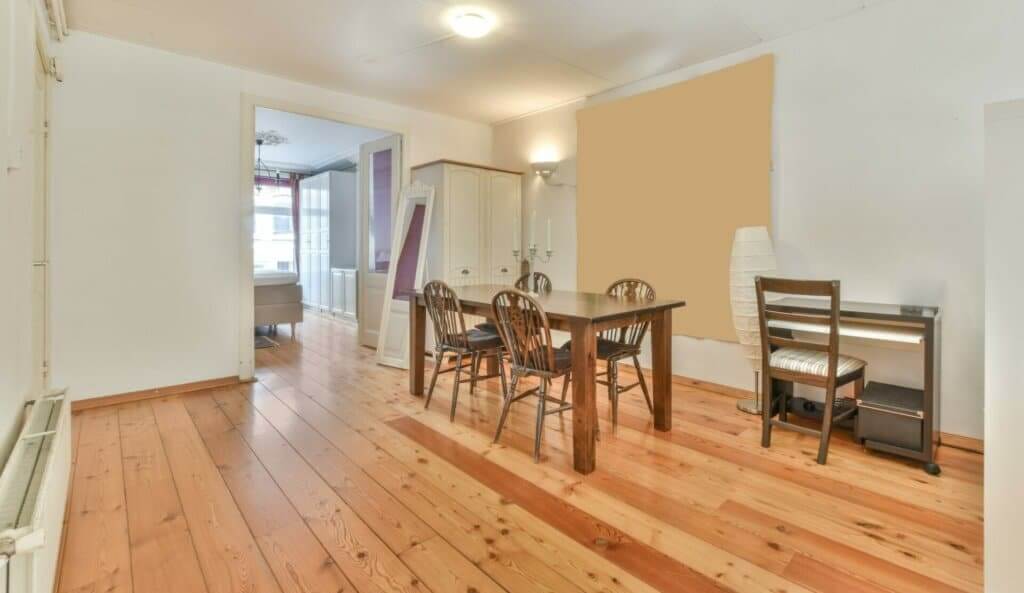 A bright dining room in South Bermondsey, UK, featuring a beautifully sanded and refinished pine wood floor by Mr Sander®. The room includes a wooden dining table, chairs, a piano, and modern decor, highlighting the smooth and polished finish of the pine flooring.