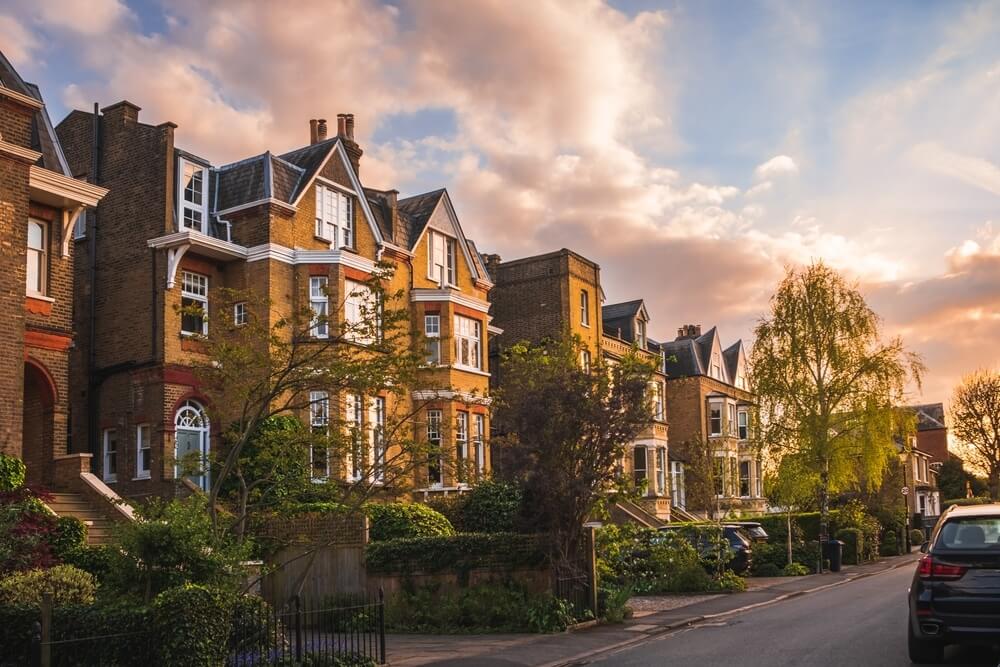 A row of elegant, traditional brick townhouses at sunset, featuring well-maintained exteriors and lush greenery. The serene residential street reflects the high-quality craftsmanship and attention to detail that Mr Sander® brings to floor sanding and refinishing services, enhancing the beauty and value of these charming homes.