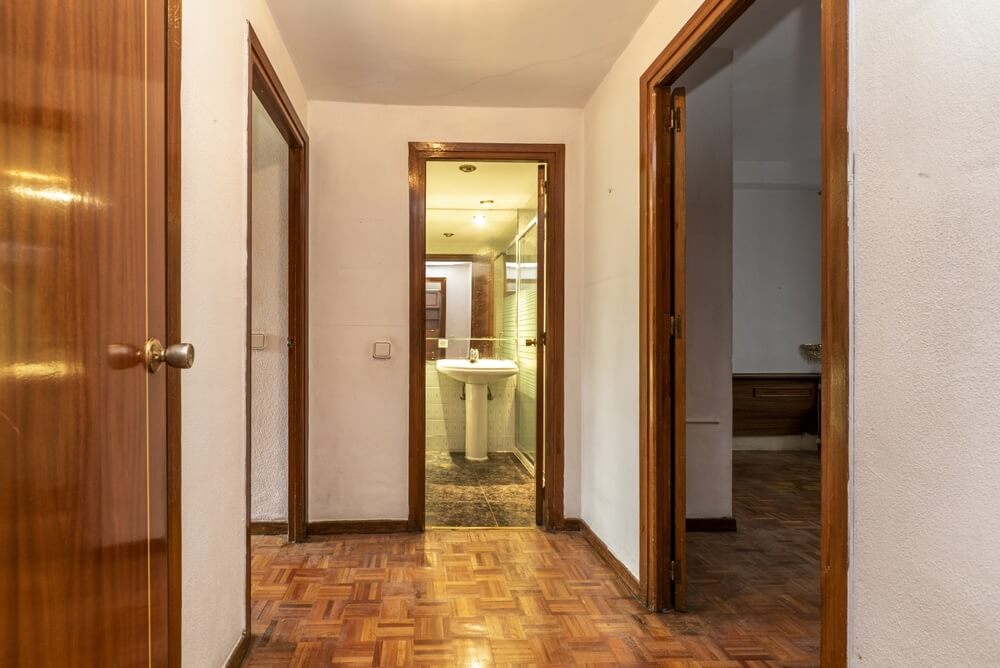 A hallway in Hanwell, UK, featuring classic parquet flooring that has been beautifully restored by Mr Sander®. The image shows the interior of a home with doors leading to various rooms, showcasing the expert floor sanding and refinishing services available in Hanwell to rejuvenate wooden floors.