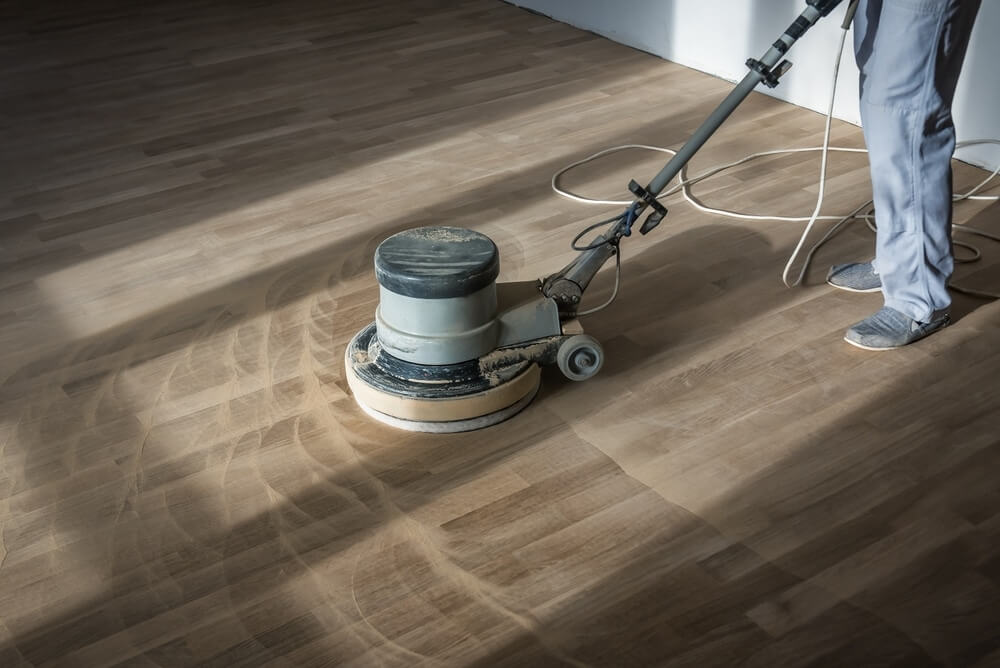 A Mr Sander® technician using a Professional Floor Sanding Machine NAW1515 (HFM1515G) by Numatic to sand an oak floor in a living area in, UK. The machine features a 1500W motor, 32kg weight, 150rpm speed, and a 450mm brush width.