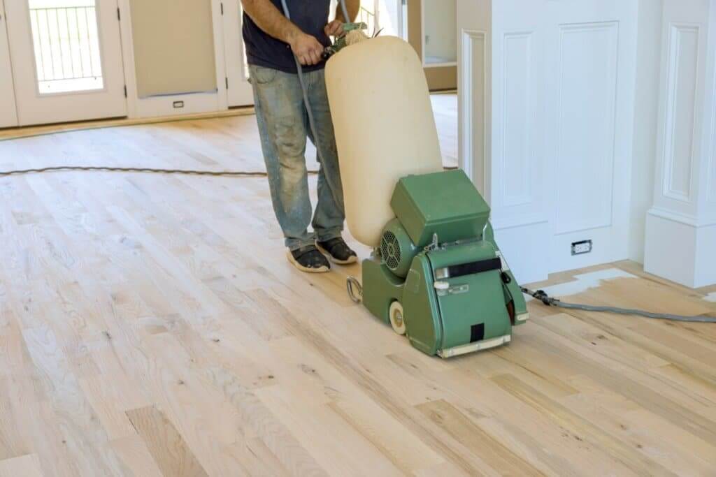 A man from Mr Sander® uses the Lagler HUMMEL®, renowned for its powerful LED lighting system, single-phase AC motor, 2.2 kW power, 2400 rpm drum speed, and 79 kg weight, for precise oak floor sanding in Farnborough, UK.