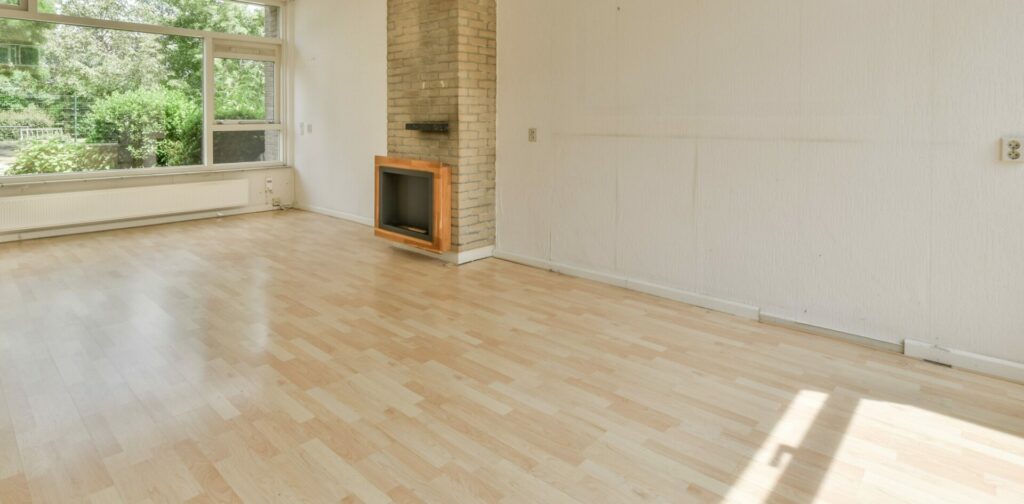 A bright, empty living room in South Lambeth, UK, featuring beautifully sanded and refinished oak floors by Mr Sander®. The space is enhanced with natural light and a garden view through large windows, showcasing the expert craftsmanship on the oak flooring.