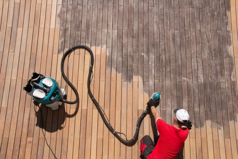 Worker using an industrial floor sander on outdoor decking.