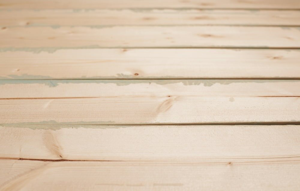 "Close-up of pale unfinished wooden planks with visible grain and joints.