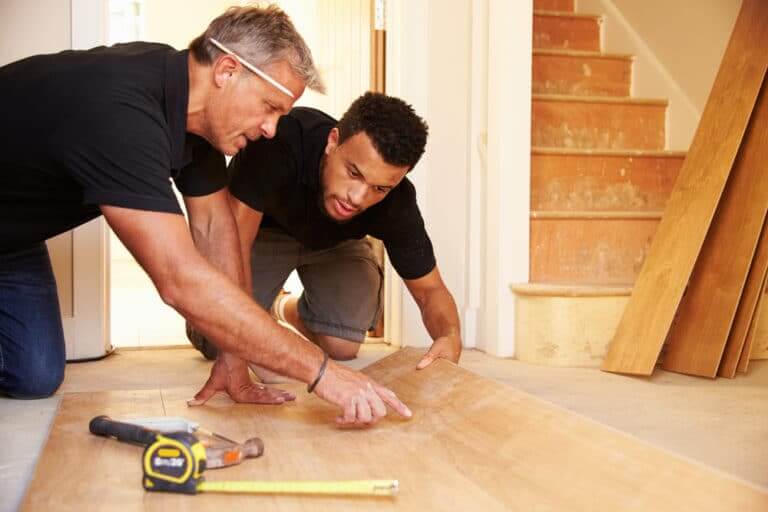 Two,Men,Laying,Wood,Panel,Flooring,In,A,House