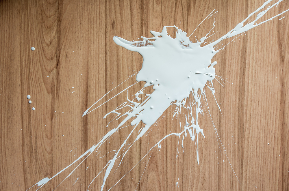 Splattered white paint on a smooth oak wood floor.