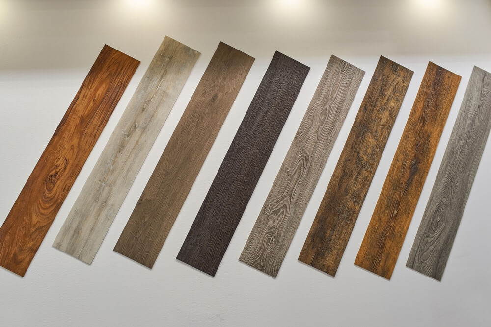 A display of various wood floor samples in different shades and finishes mounted on a wall. The samples showcase a range of colors and wood grain patterns, providing options for floor sanding and refinishing projects.