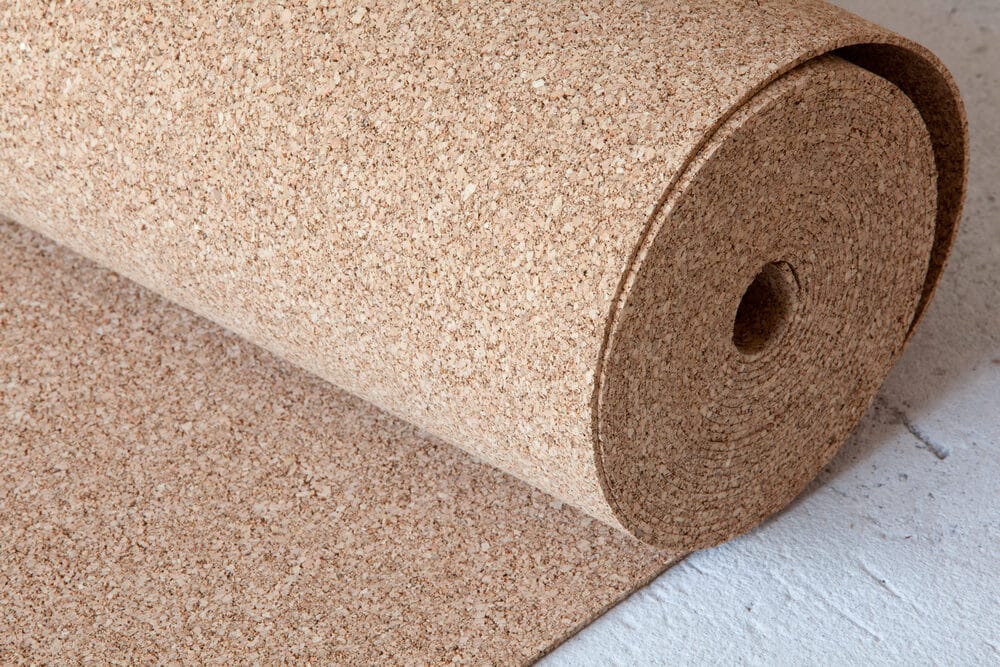 A roll of cork material partially unrolled on a concrete surface.