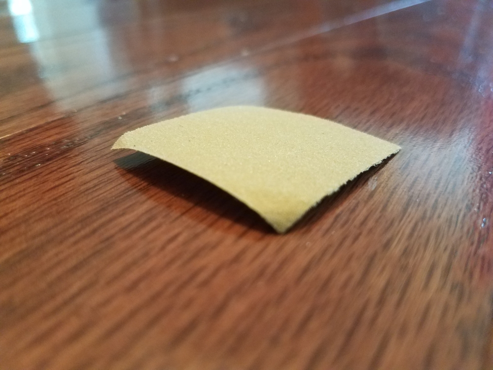 A piece of sandpaper on a wooden surface.