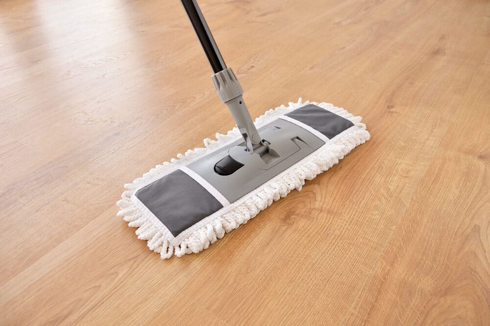 A flat mop with a microfiber pad gliding over a smooth laminate floor.