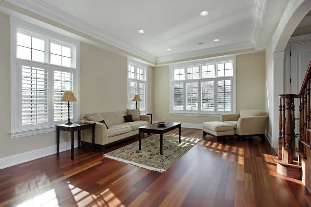 A beautifully restored hardwood floor in a living room in South Norwood, UK. The space is bright and welcoming, with sunlight streaming through large windows, highlighting the rich tones and smooth finish of the wooden flooring.