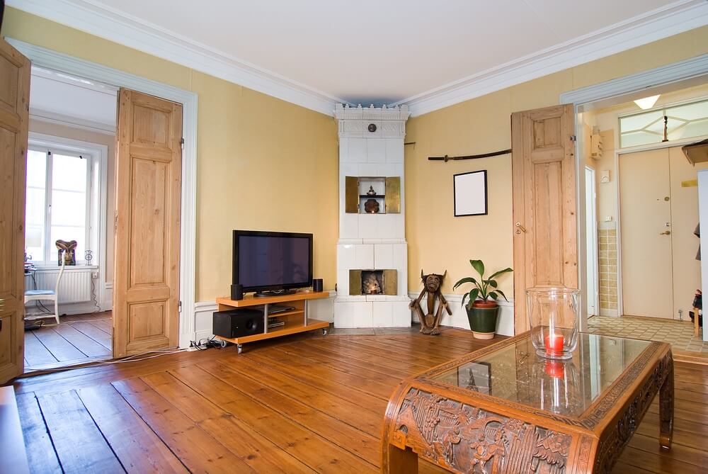 A cozy living room in Upminster with restored wooden flooring, traditional furniture, and a tiled fireplace.