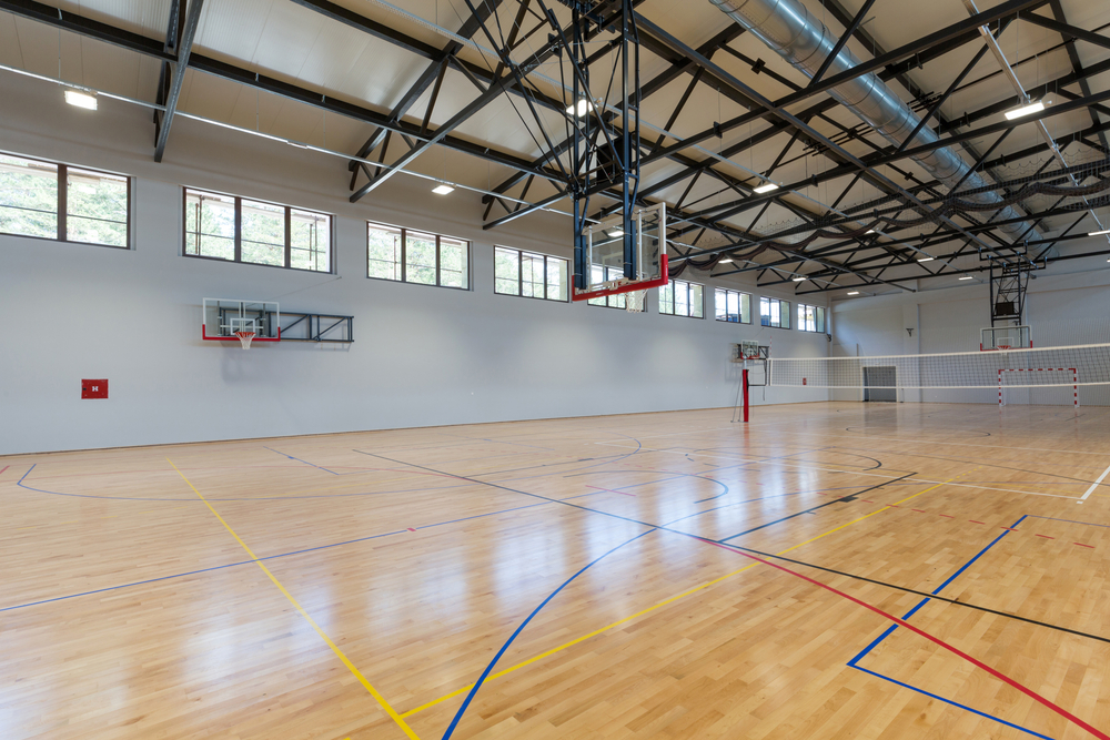 Bright multi-court maple hardwood sports hall floor after Sports Hall Floor Sanding, showing smooth timber surface and clear court markings.