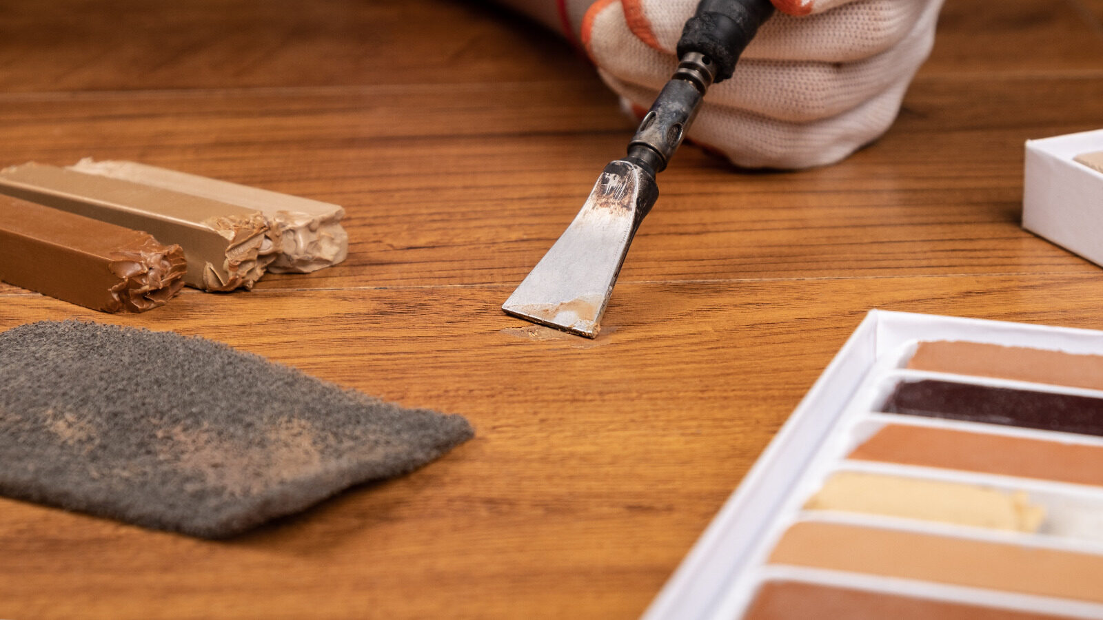 Spot Repair on oak hardwood plank floor using a hot knife to melt colour-matched hard-wax filler into a small chip before levelling and buffing
