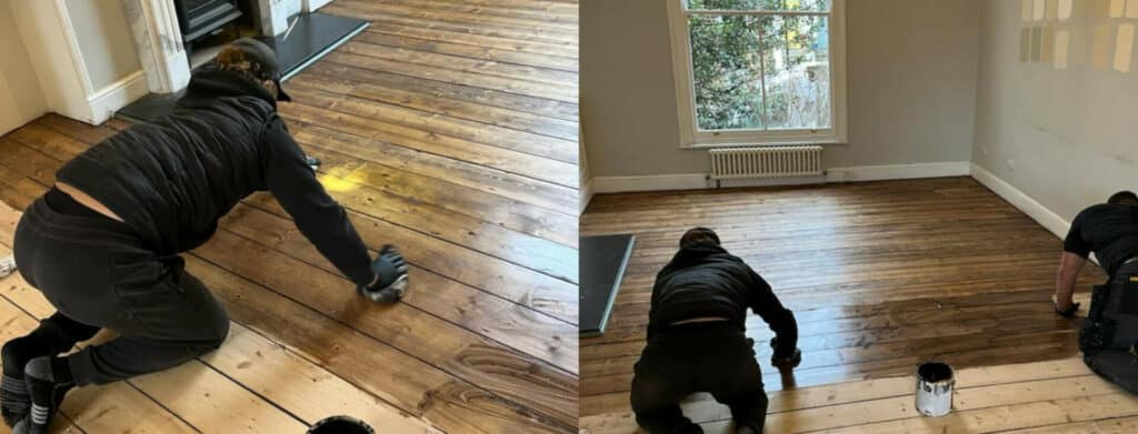 Two workers are kneeling on the floor, applying wood stain to large wooden floorboards. The image on the left shows one worker carefully applying the stain, darkening the wood, while the image on the right shows the same room with more of the floor stained, revealing the rich, darker tones of the wood. Natural light from the window highlights the transformation process.