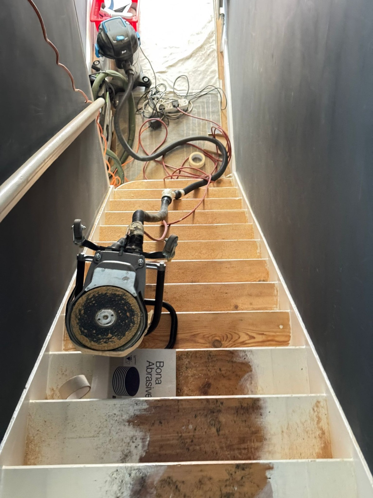 Professional floor sanding equipment being used on a Staircase Revival project to remove paint and prep pine wood treads for finishing.