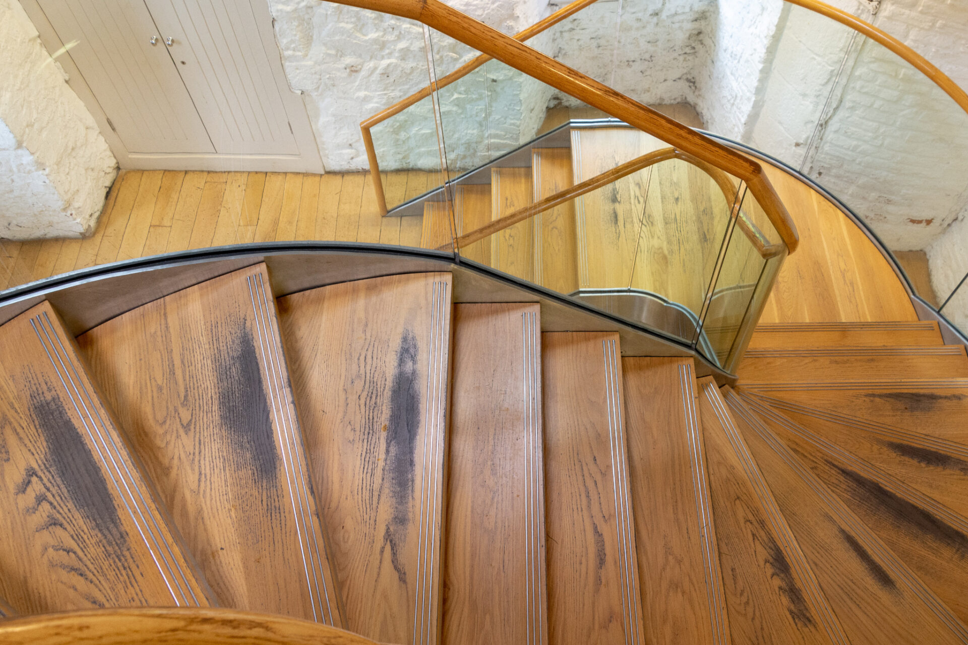 Curved oak timber staircase with worn treads and anti-slip strips awaiting professional Staircase Sanding in London to restore the solid oak wood floor steps.