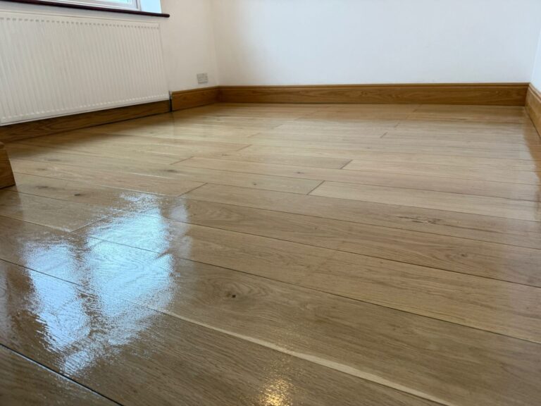 The 5-Minute Spill Test on an oak engineered wood floor with satin lacquer finish—water beading shows the sealer still working.