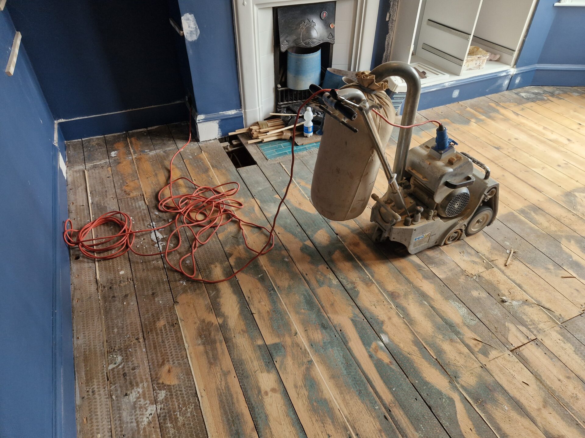 Timber Floor Restoration on original pine softwood floorboards, with a drum sander stripping old paint and stain from a worn timber floor.