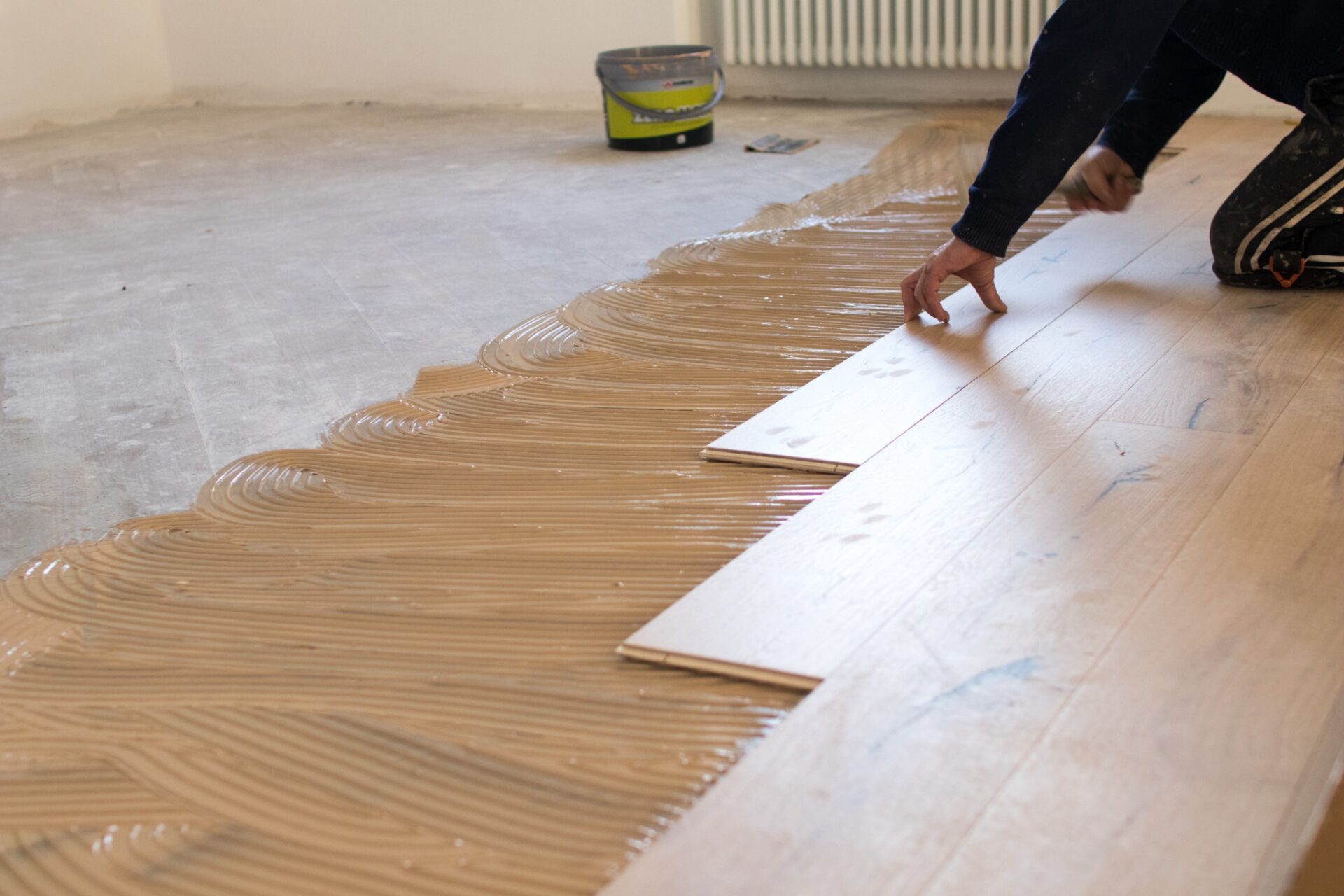 Mr Sander expert performing Floor Installation of wide oak timber boards in an urban apartment with fresh adhesive.