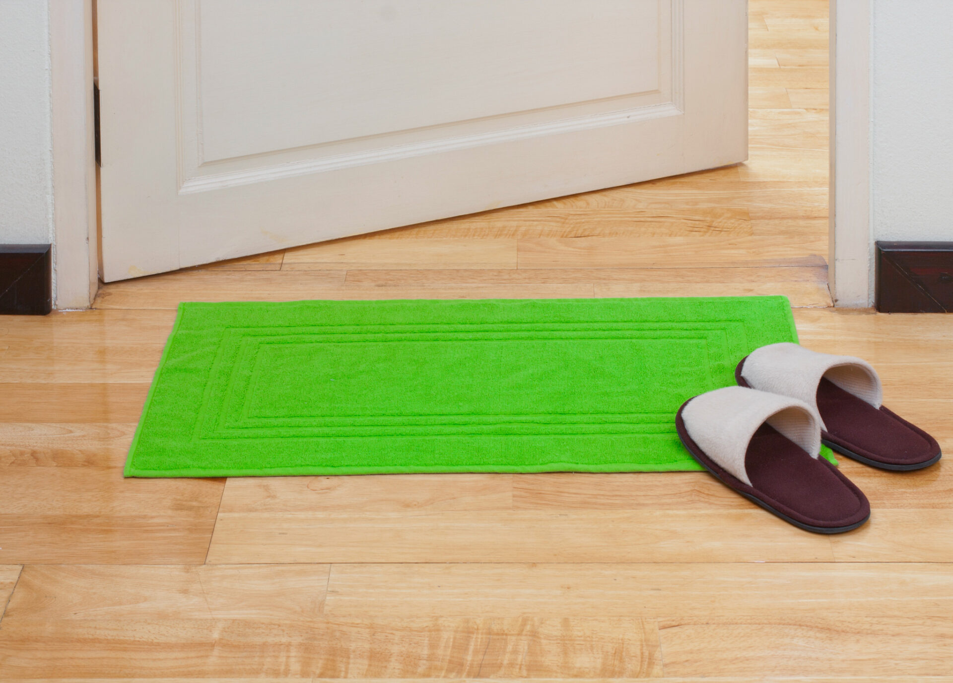 Victorian Pine Floor protection—natural softwood pine floorboards with a bright green doormat and slippers placed near a doorway to prevent wear.