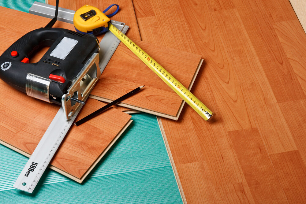 Tools and materials prepared for Wood Floor Fitting with cherry-effect laminate flooring panels.