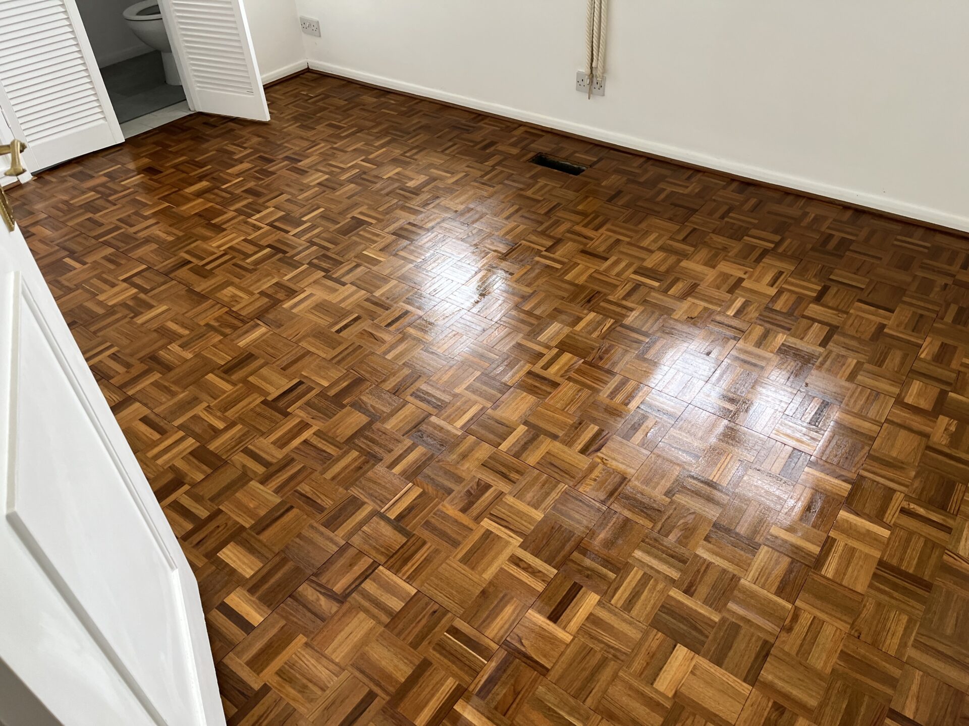 Wood Floor Restoration on oak finger-block parquet (hardwood), showing a freshly sanded and lacquered surface with an even, reflective sheen.