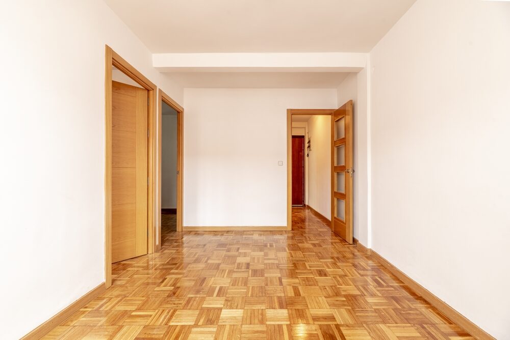 Wood Floor Restoration on oak finger-block parquet (hardwood) in a bright empty room, showing a smooth, freshly lacquered finish with even sheen.