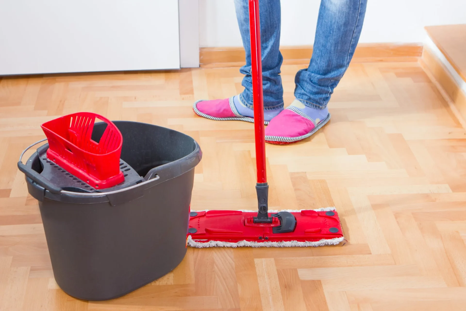 After Wood Floor Sanding, a light oak parquet block floor being gently cleaned with a flat mop and bucket as part of simple aftercare