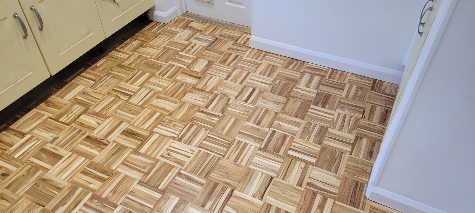 Freshly restored oak mosaic parquet wood floor in a kitchen after Wood Floor Sanding in London, showing clean, natural grain and an even finish.